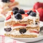 A slice of strawberry, blueberry and cream cake on a plate.