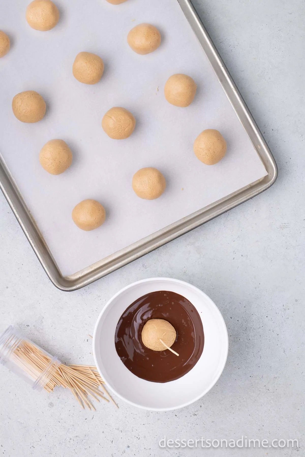 Bowl of melted chocolate with a peanut butter ball being dipped.
