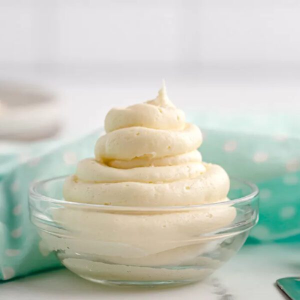 A bowl of whipped cream sits on a table.
