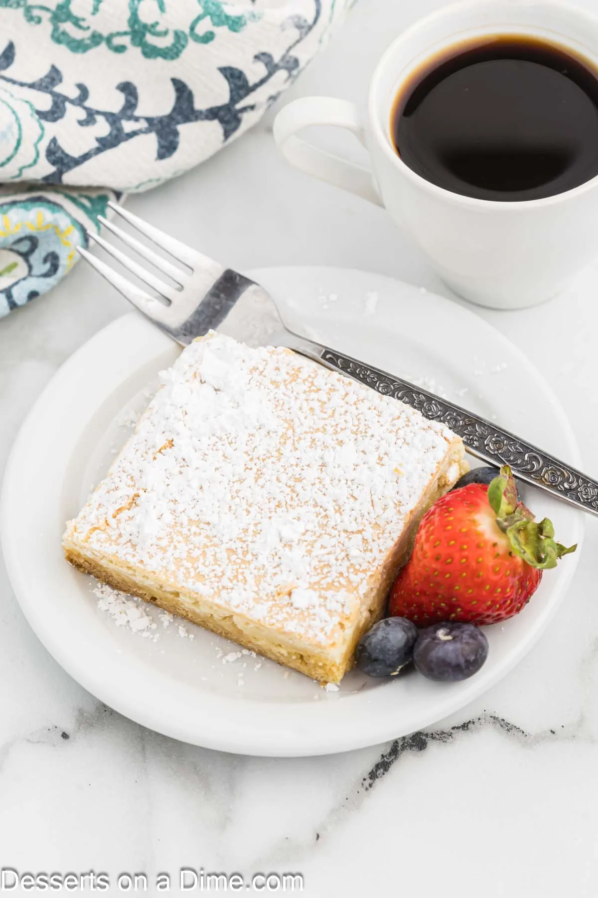 Paula Deen Ooey Gooey Butter Cake cut into squares and served on a plate with fruit.