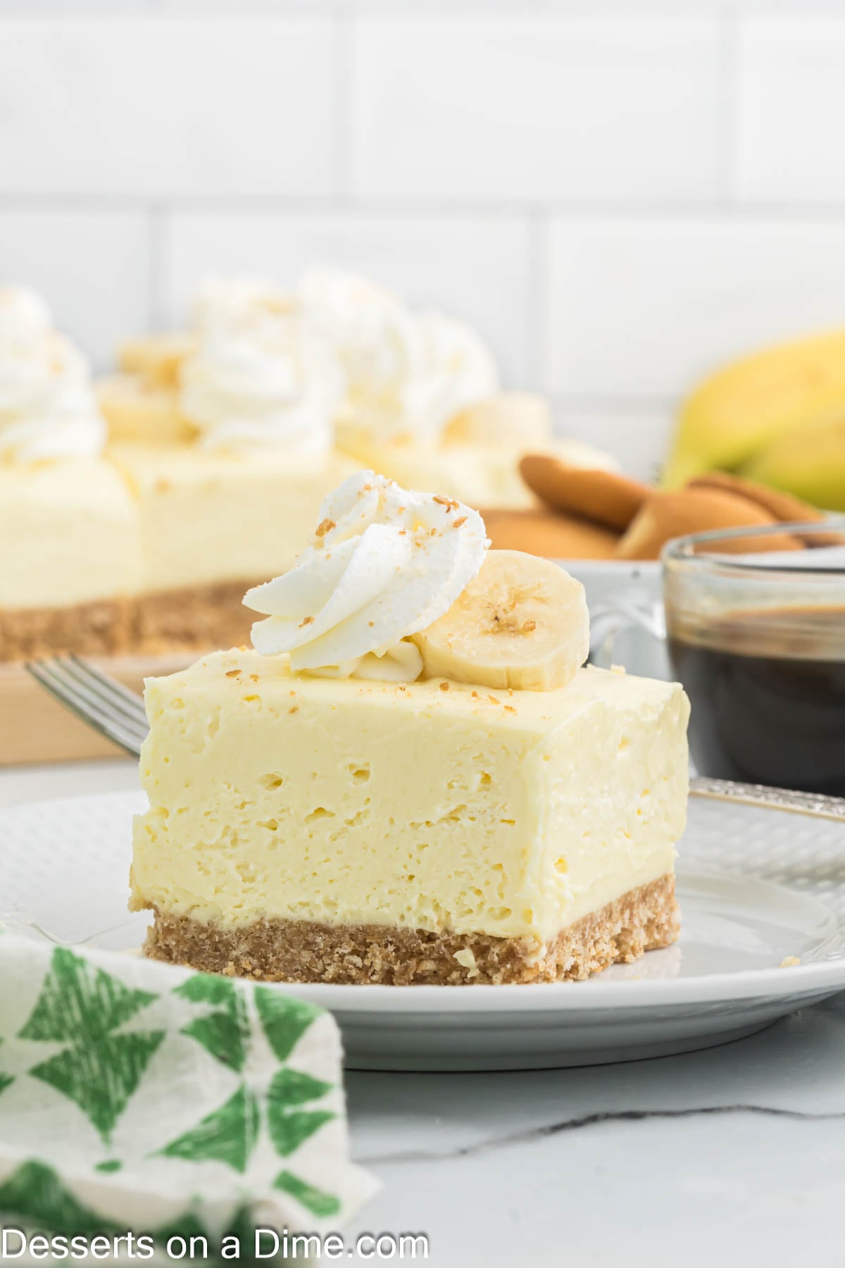 Banana Cheesecake Bar on a plate topped with whipped cream and banana slices. 