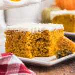 Pumpkin bars with cream cheese frosting on a white plate.