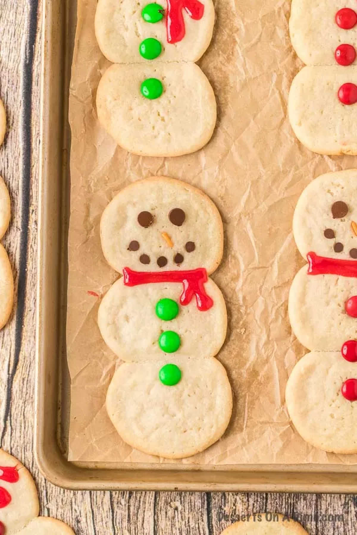 Snowman cookies on baking sheet lined with wax paper. 