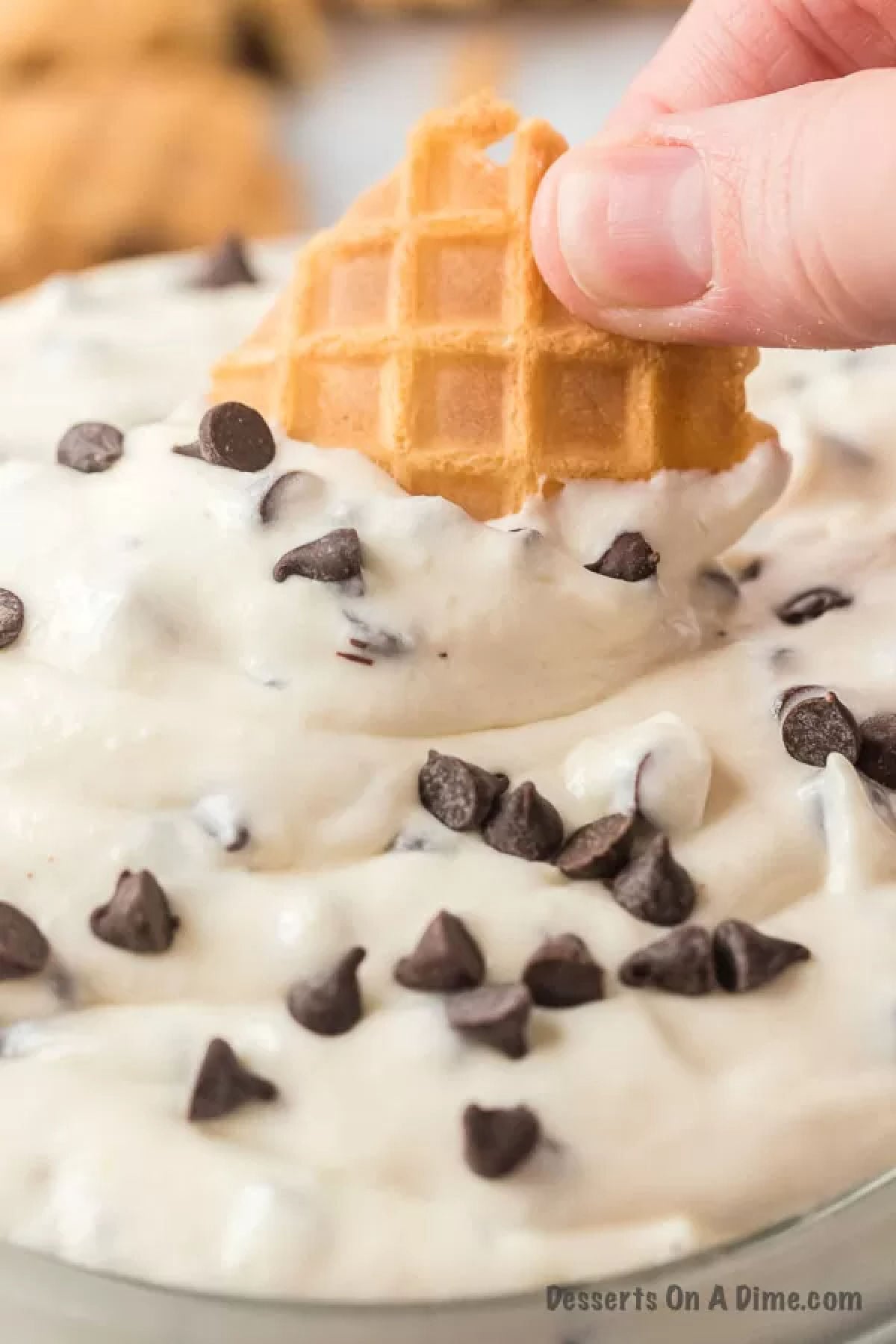 Waffle cone being dipped in dip. 