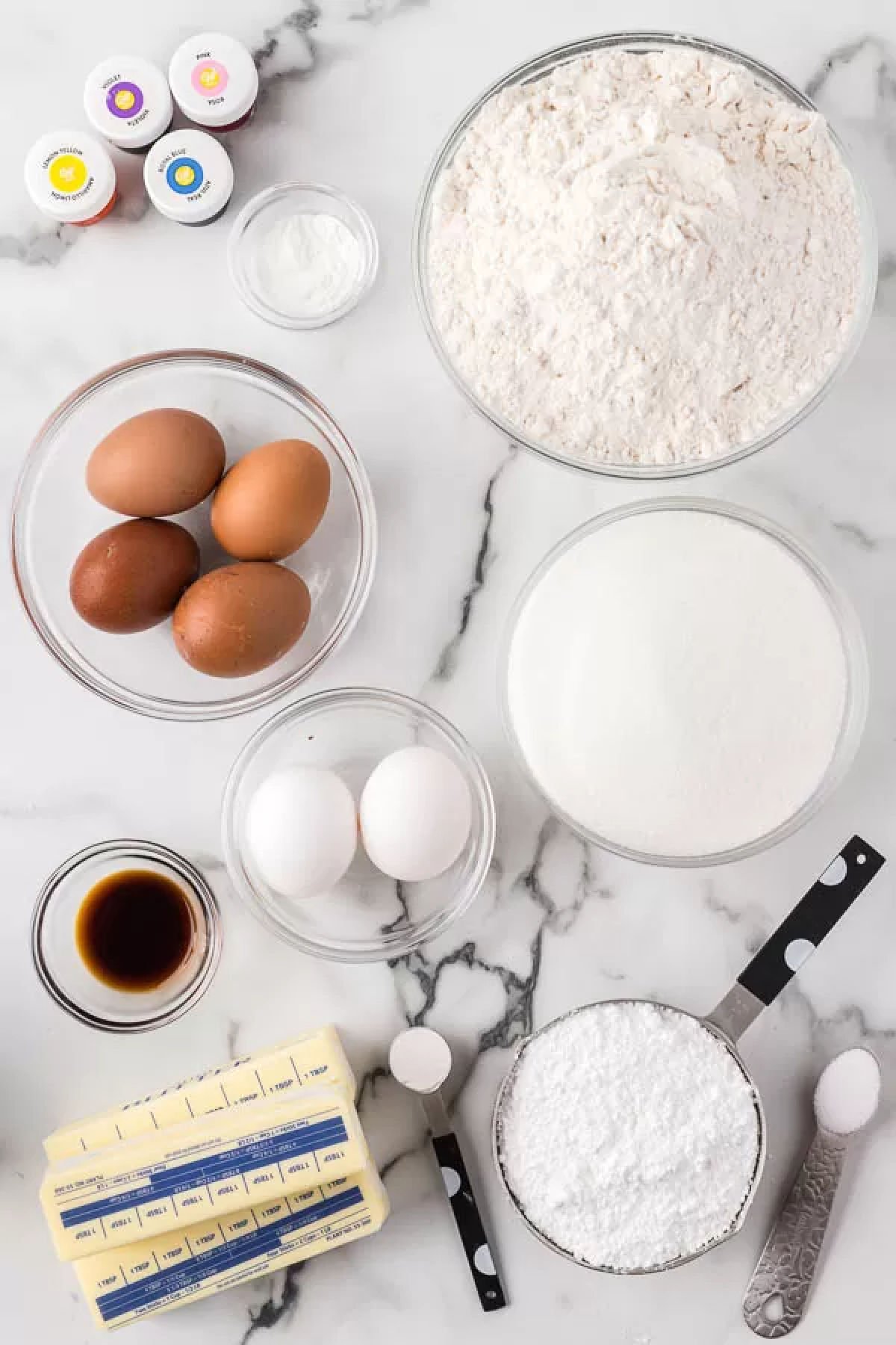 Ingredients for recipe - flour, butter, eggs, vanilla extract, egg whites, powdered sugar, cream of tartar, gel food coloring.