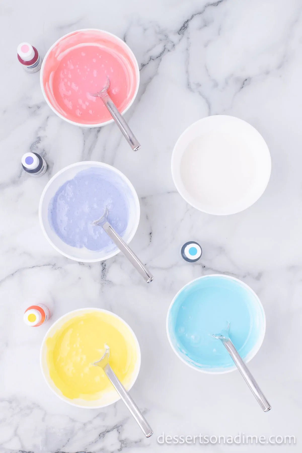 Icing in bowls with different colors of food coloring.