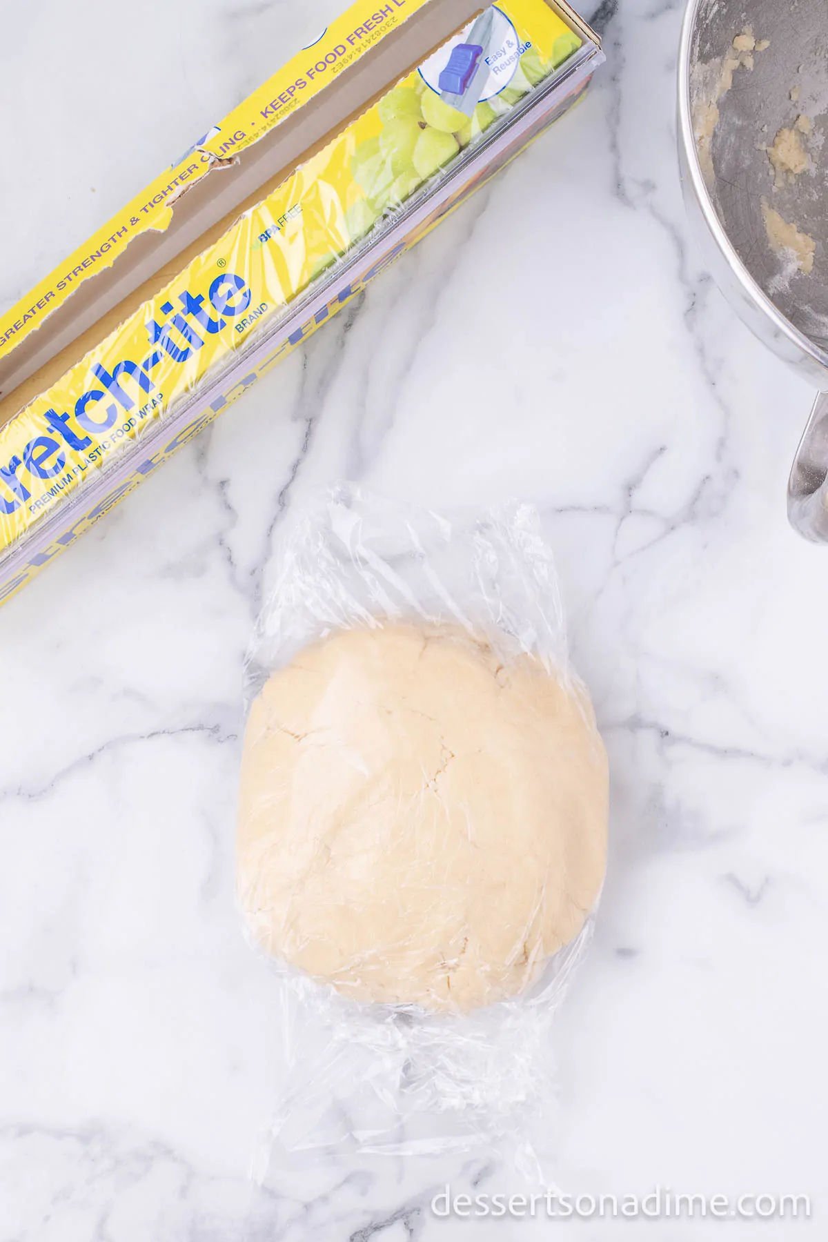 Dough in a ball wrapped in plastic wrap.