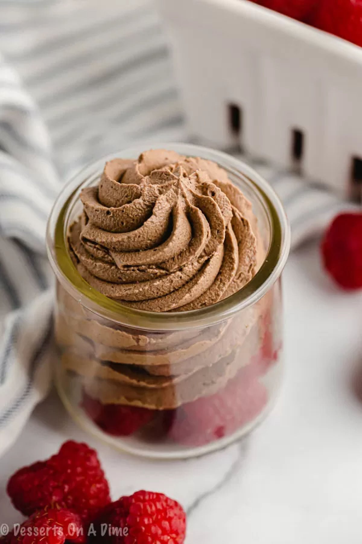 Keto chocolate mousse is ready in only 5 minutes for the perfect Keto friendly dessert in minutes. Make this for a decadent treat you can enjoy in minutes. Keto Chocolate Mouse piped on top of fresh raspberries.