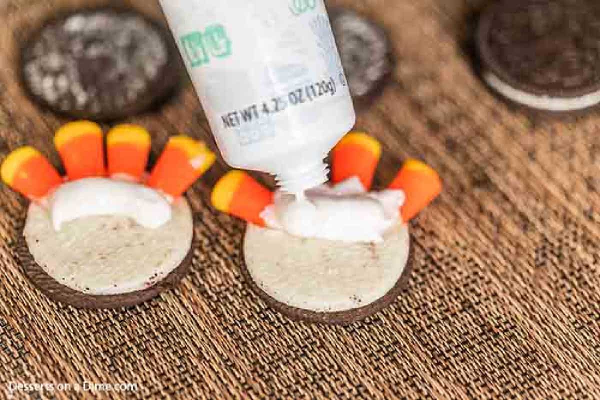 Icing being placed on the bottom of the candy corns. 