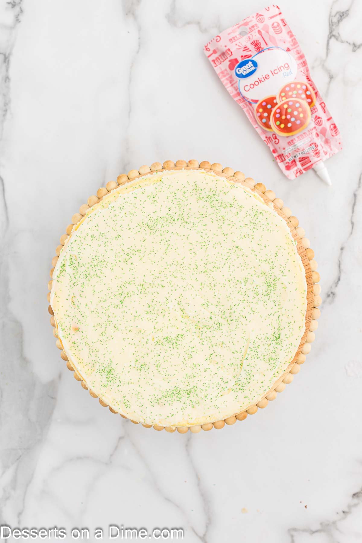 Ganache poured over cheesecake and topped with green sugar sprinkles. 