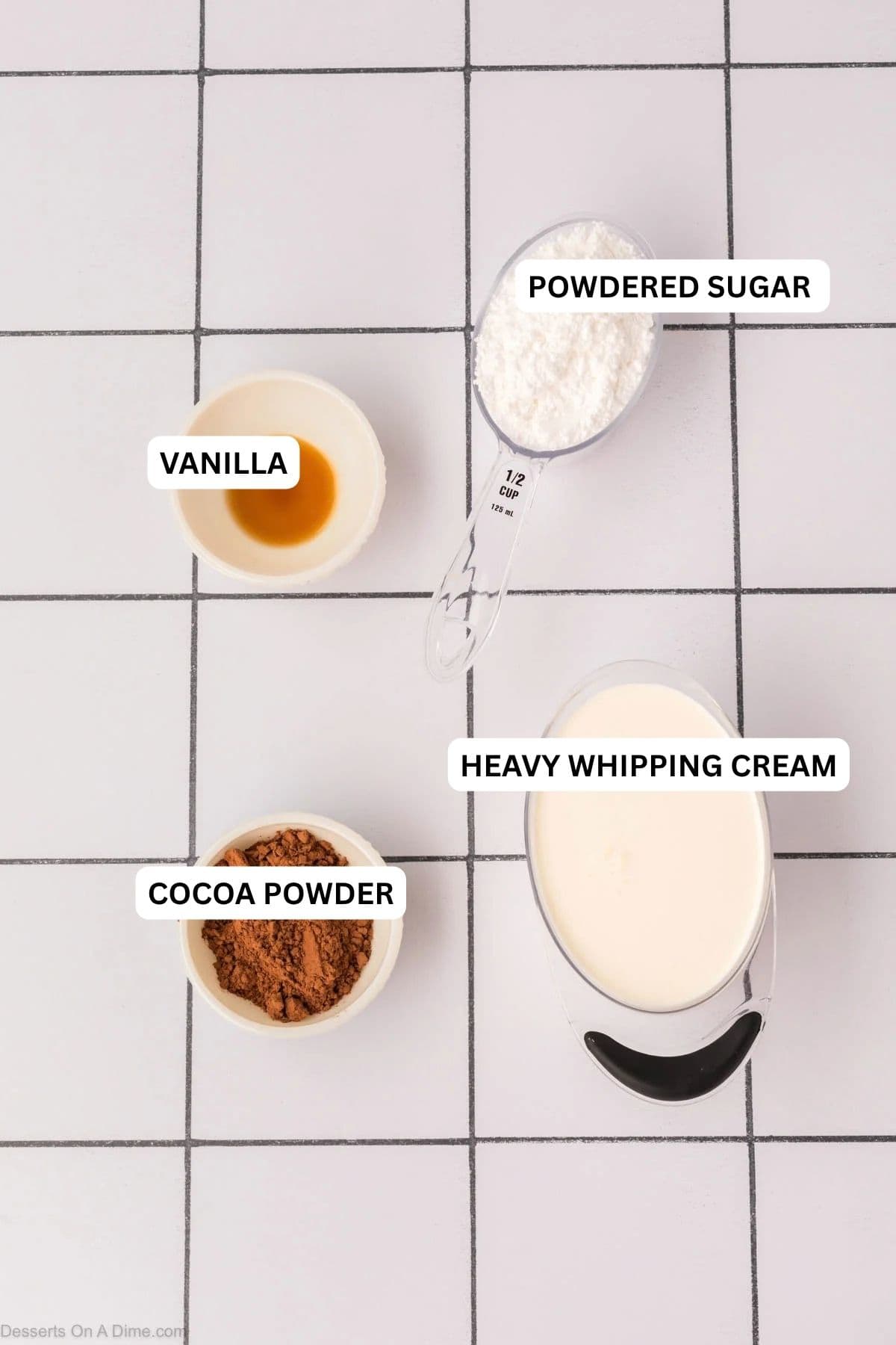 Heavy cream, cocoa powder, powdered sugar, and vanilla on a counter.

