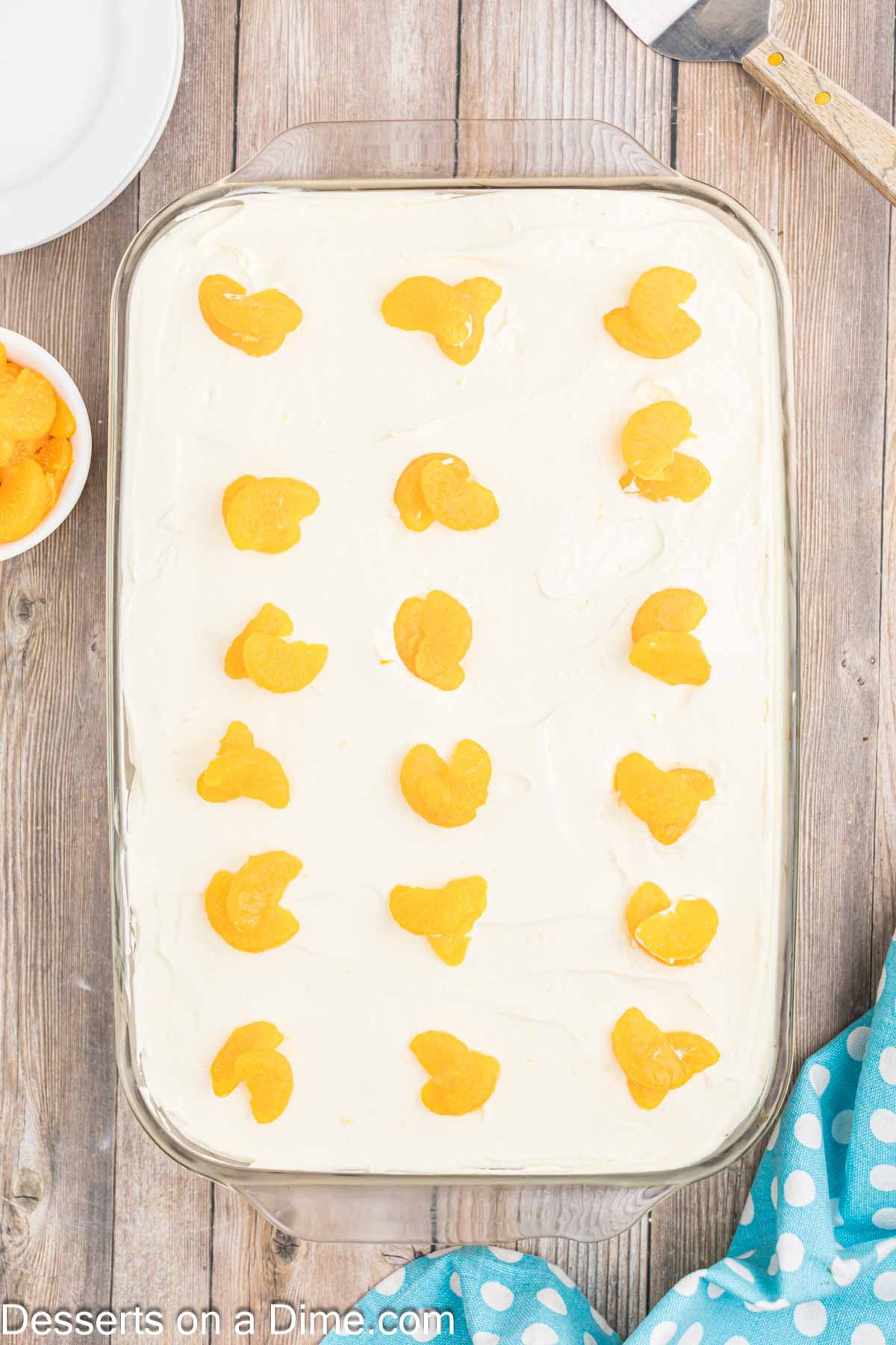 Frosting spread on cake with oranges.