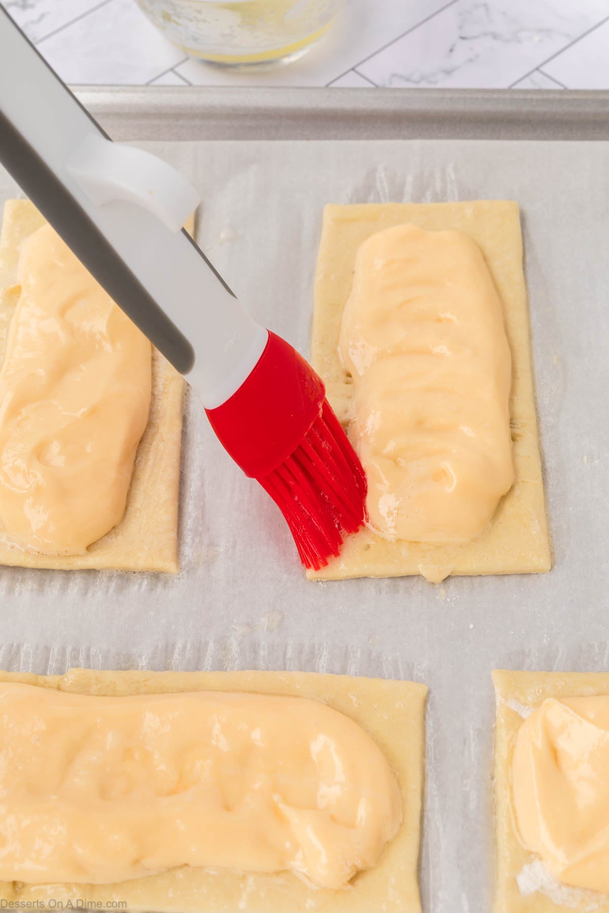 Pastry brush brushing egg whites on sides.
