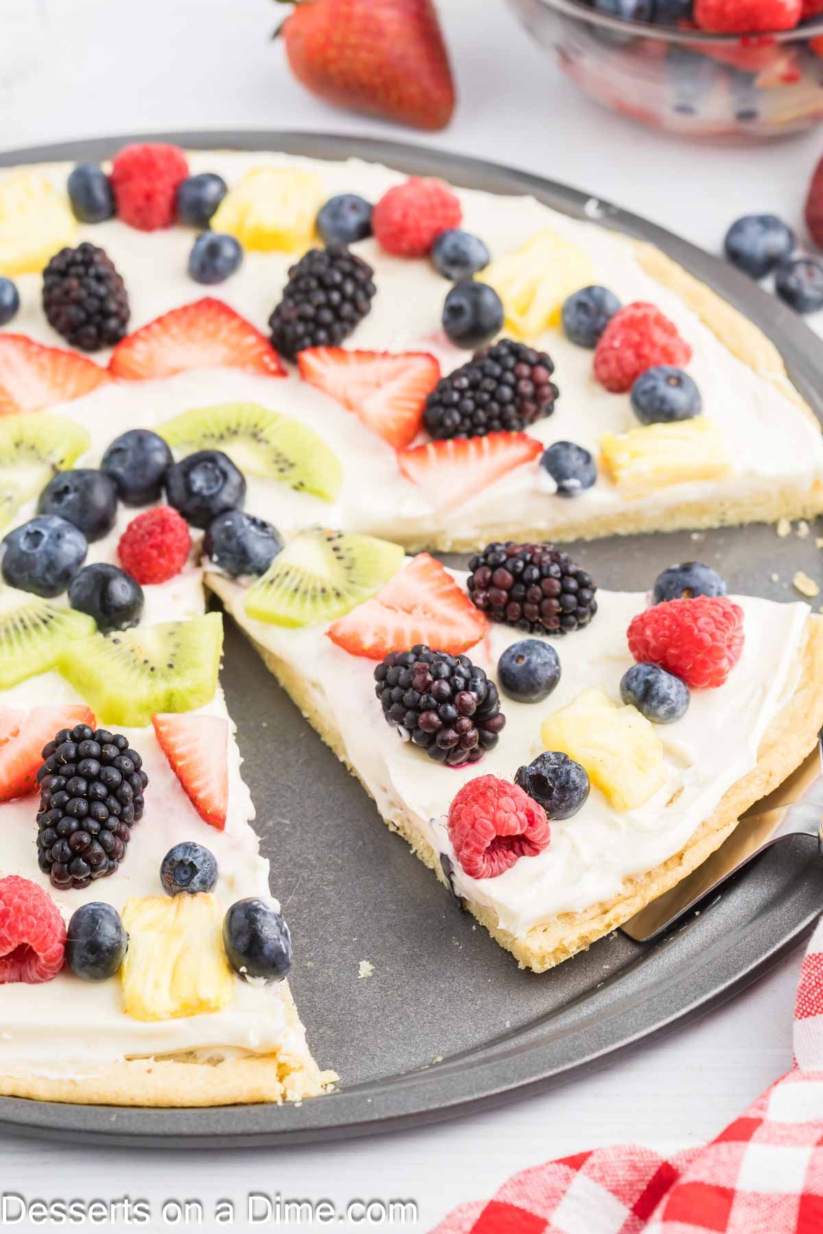 Fruit pizza being sliced and served.