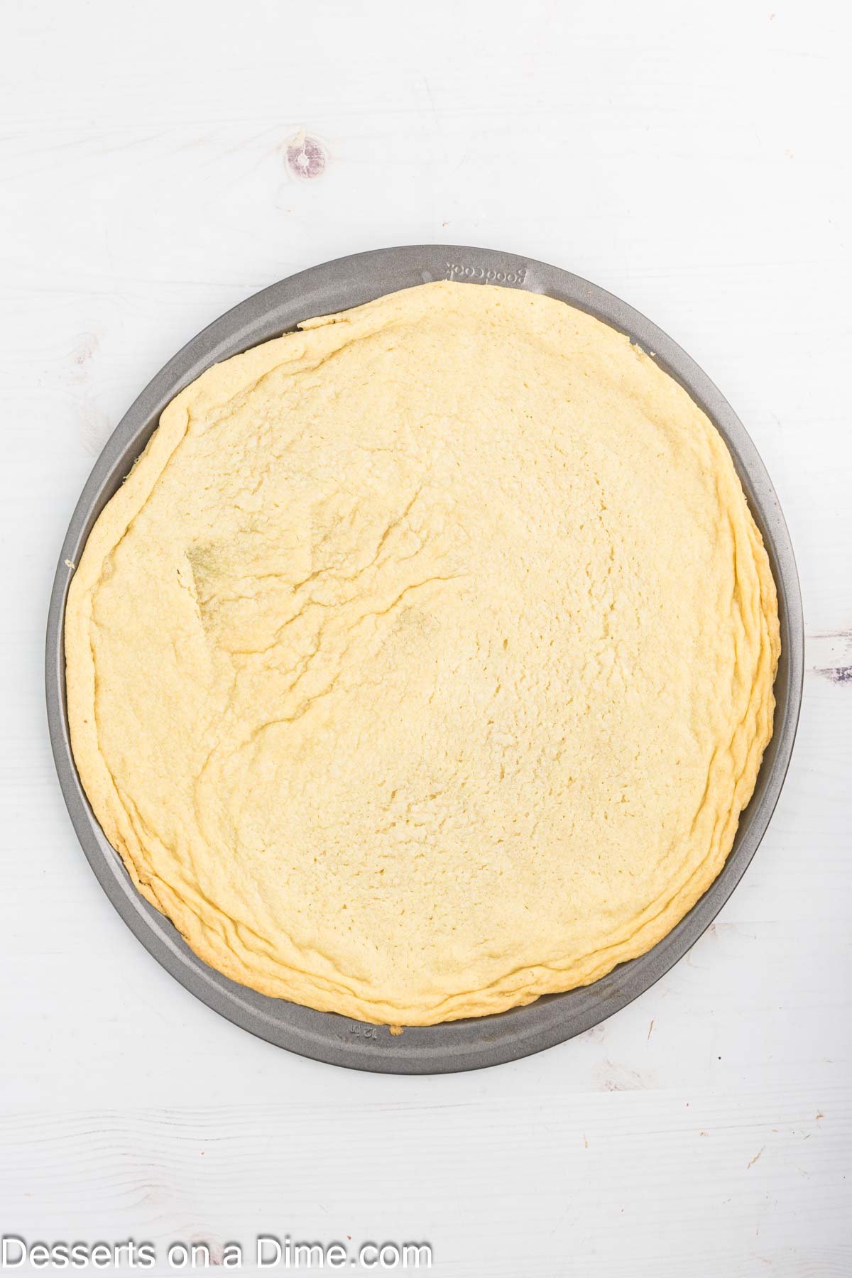 Cookie dough crust spread on pizza pan.