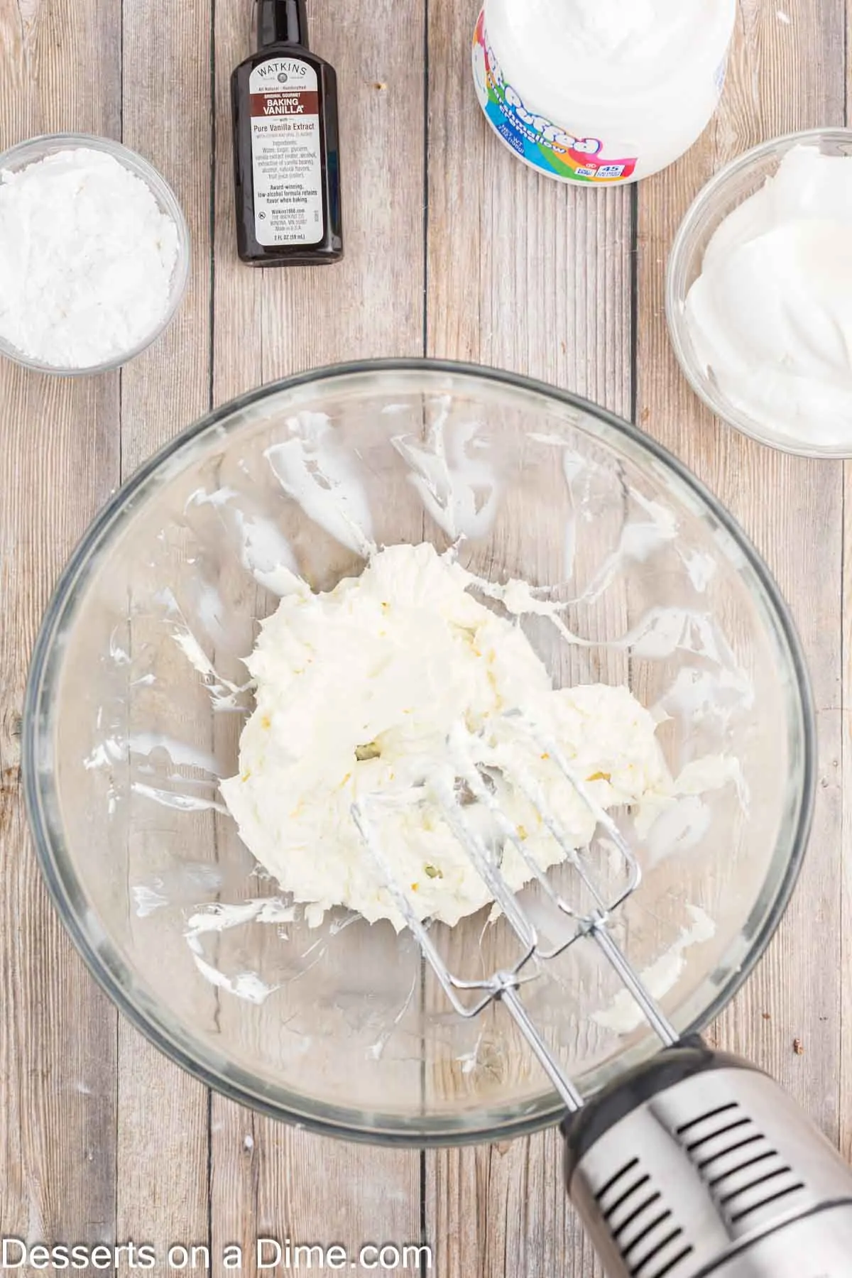 Mixer beating cream cheese in bowl on medium speed.