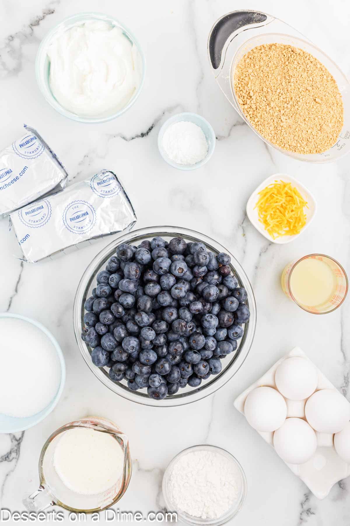 Ingredients - graham cracker crumbs, sugar, unsalted butter, cream cheese, sour cream, lemon juice, lemon zest, eggs, blueberries, sugar.