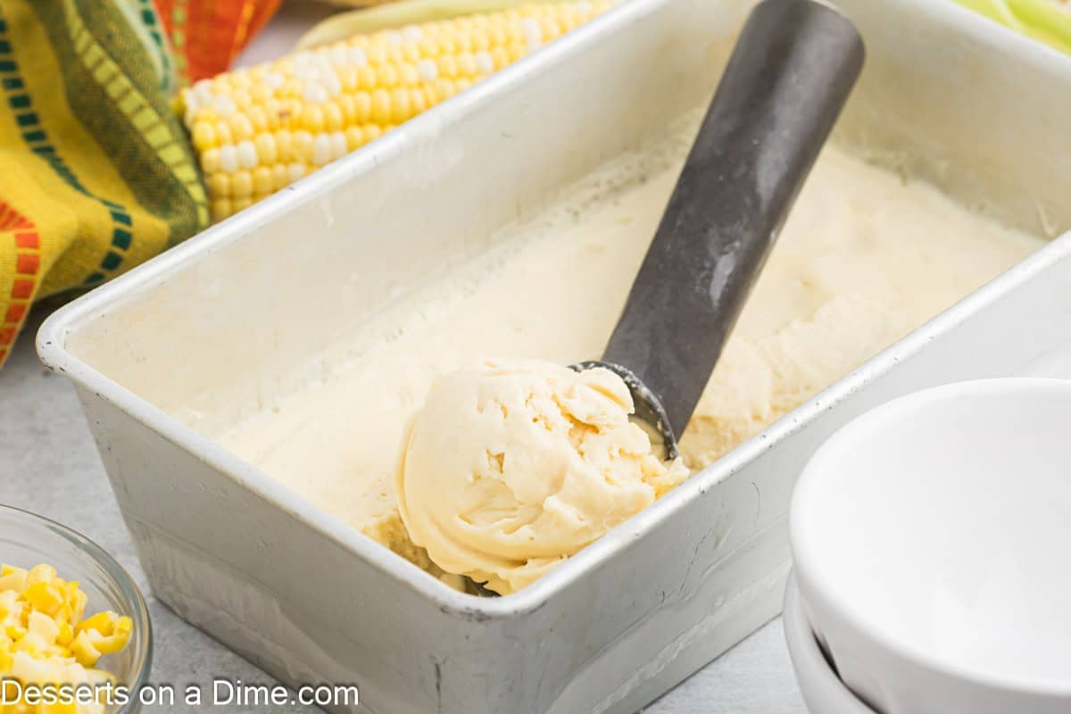 Container of corn ice cream being scooped.