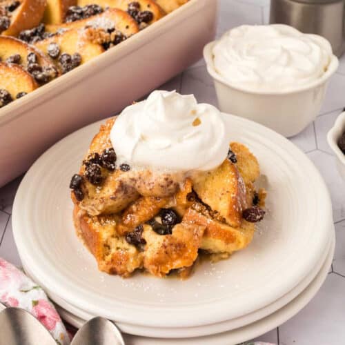 Plate with bread and butter pudding topped with whipped cream.