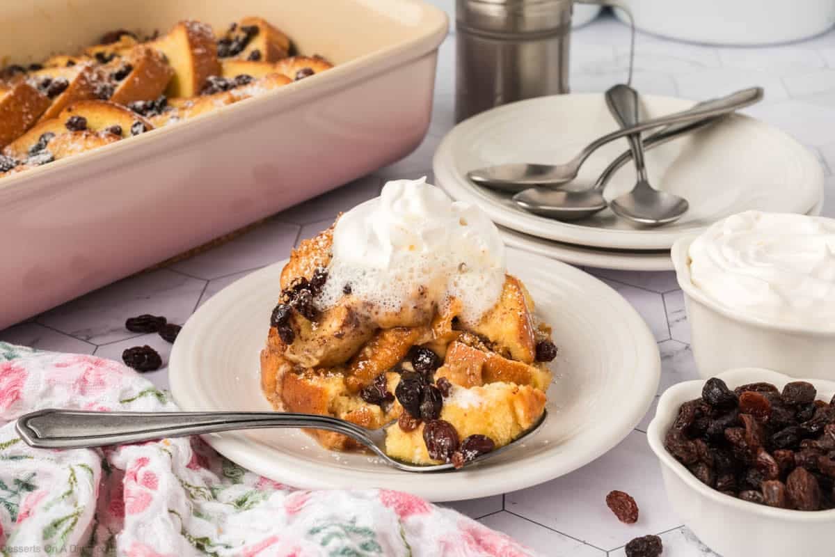 Bread pudding on a plate topped with whipped cream.