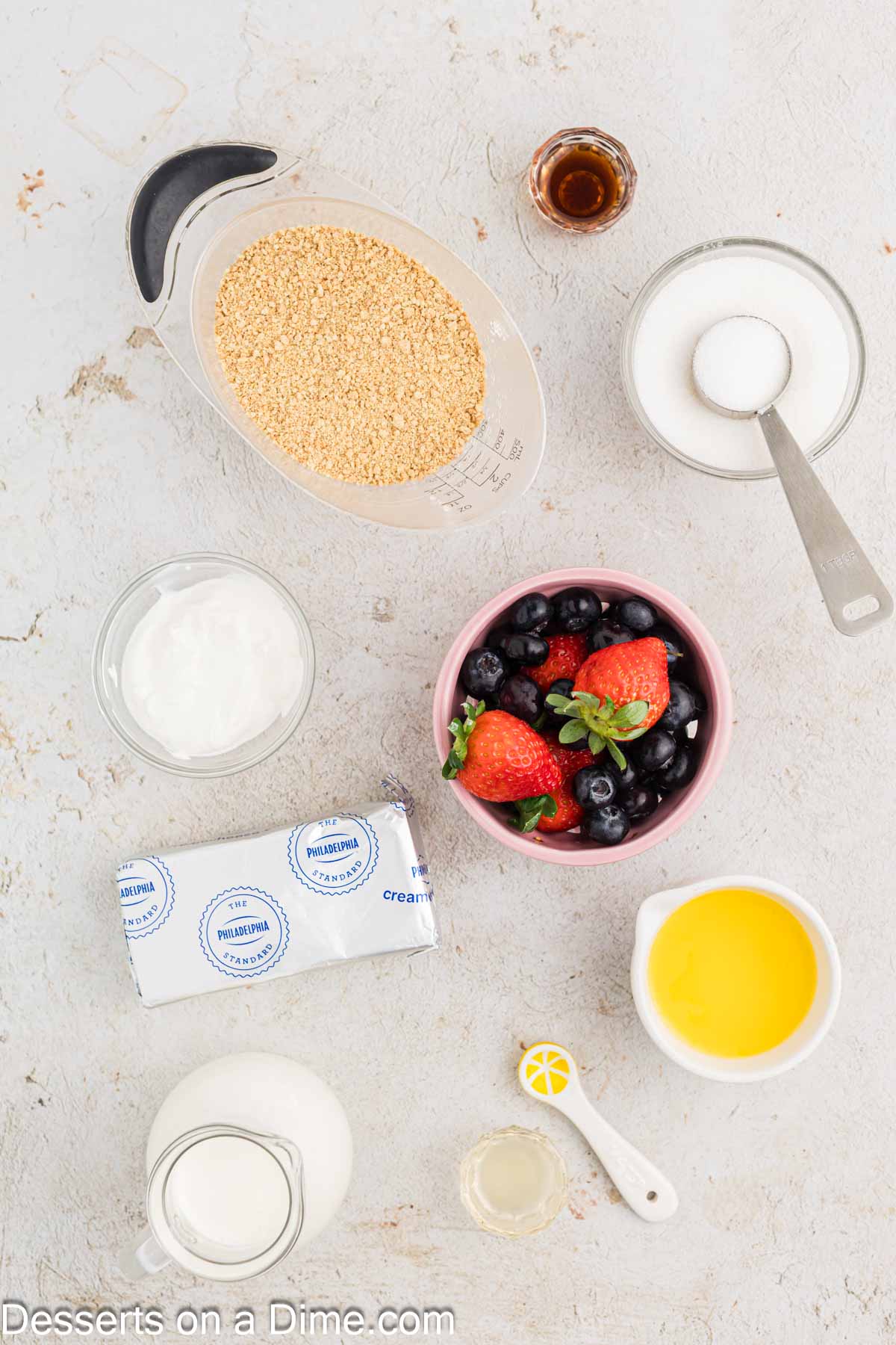 Ingredients for mini cheesecake bites - graham crackers, sugar, butter, heavy cream, cream cheese, sour cream, lemon, vanilla, berries. 
