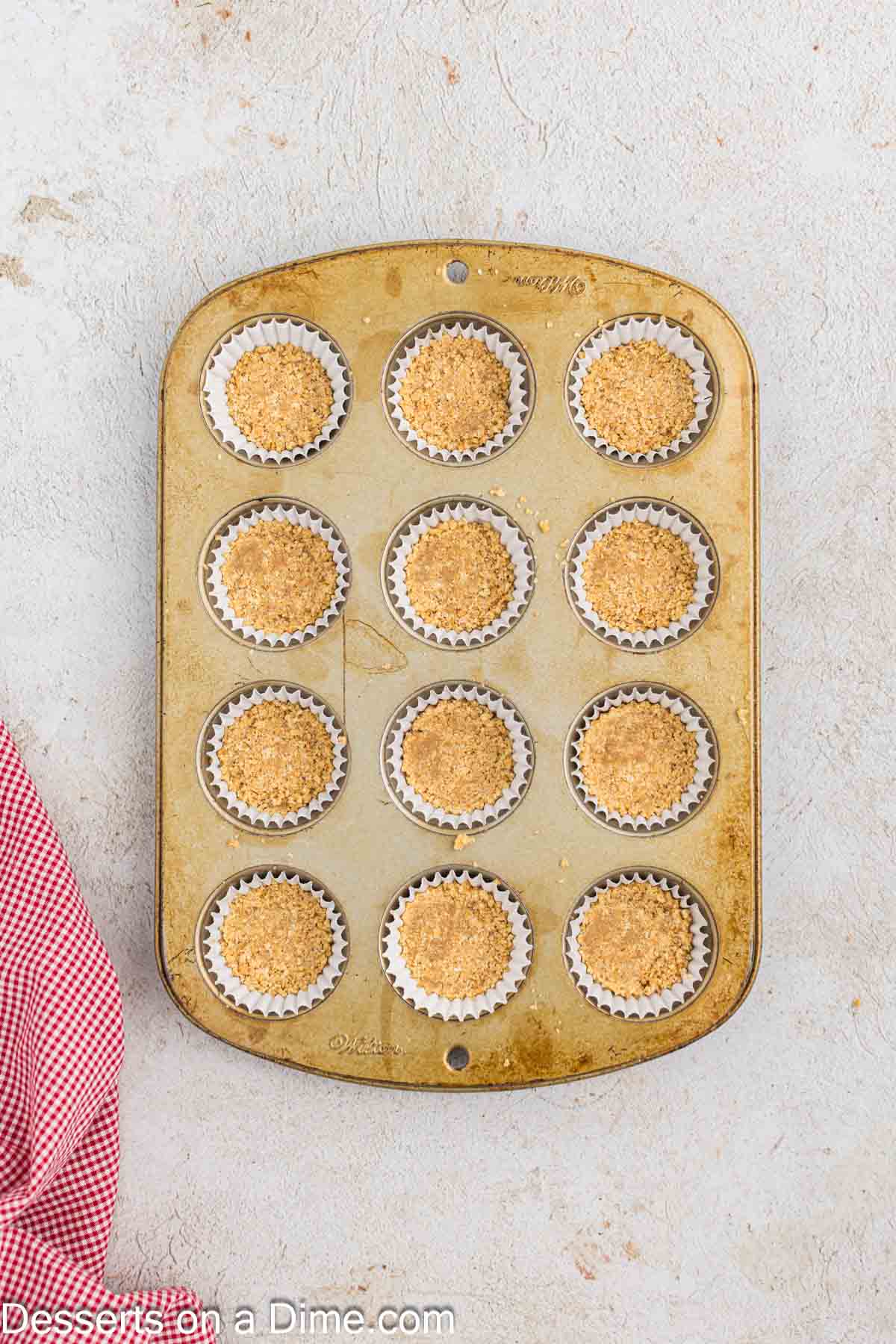 Graham cracker crumbs in mini muffin tin. 