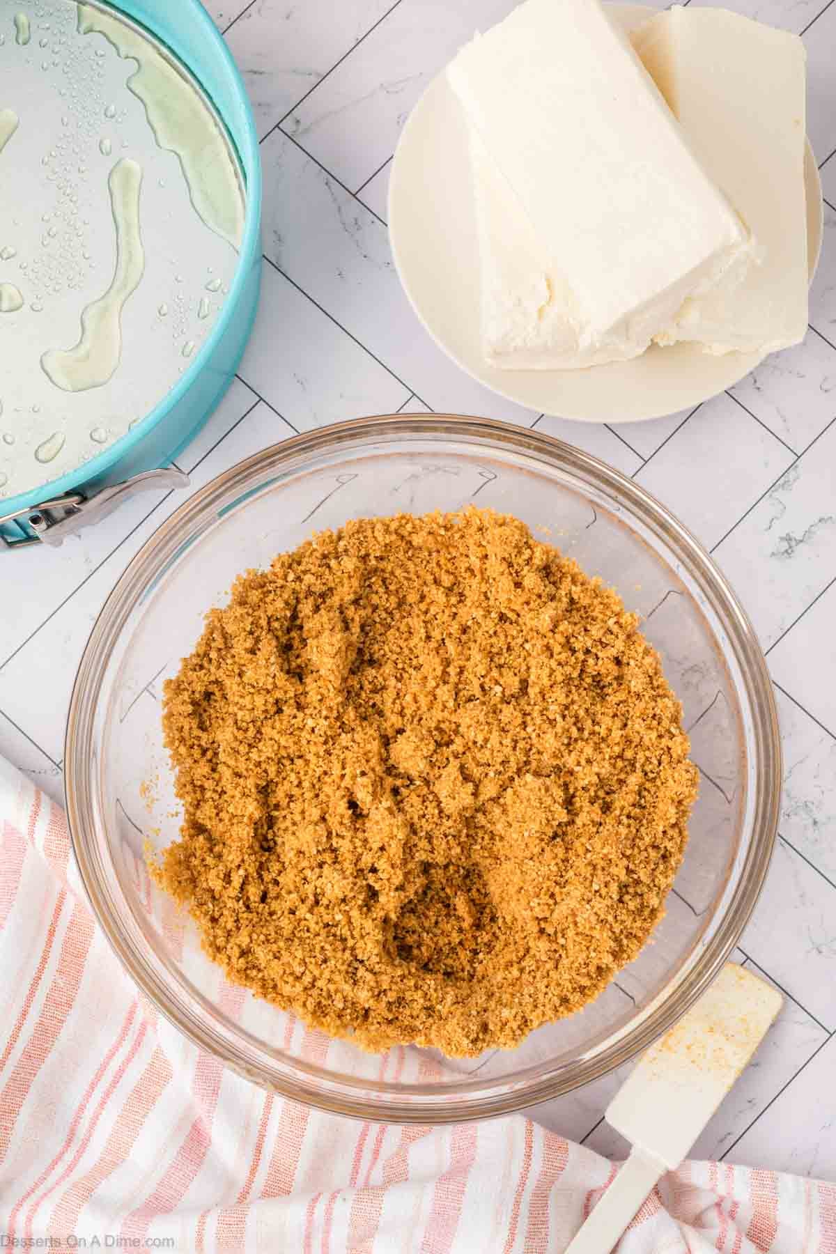 Graham cracker crumbs combined with butter in a bowl. 