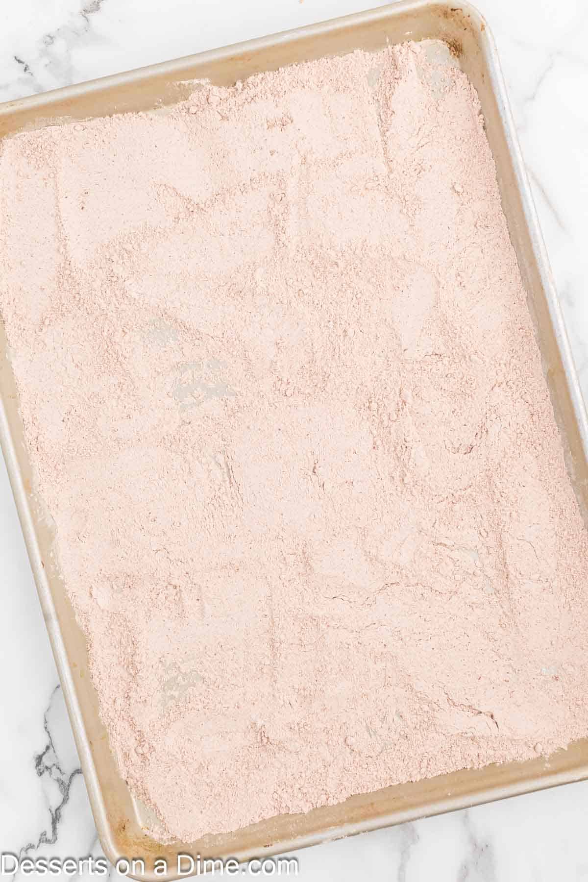 Cake mix spread on baking sheet. 