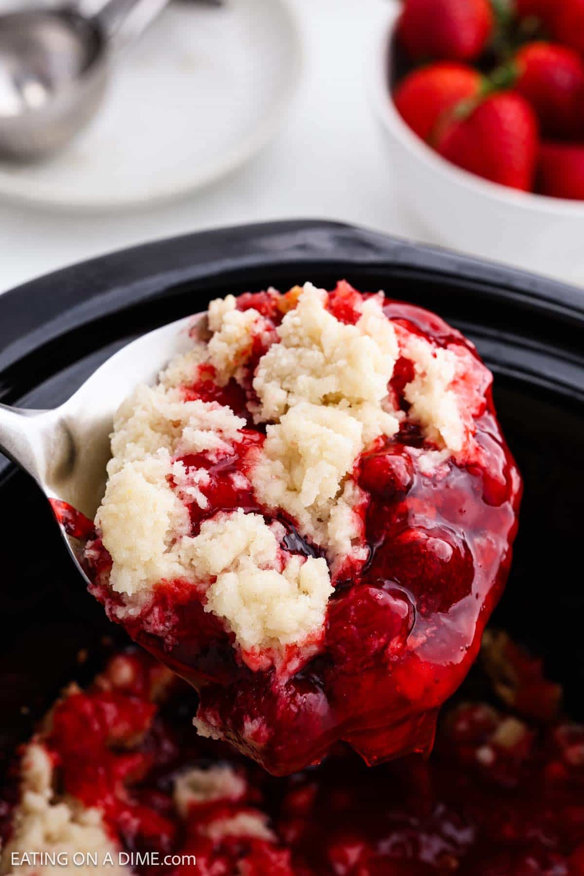 Spoon in slow cooker with Strawberry Dump Cake ready to serve. 