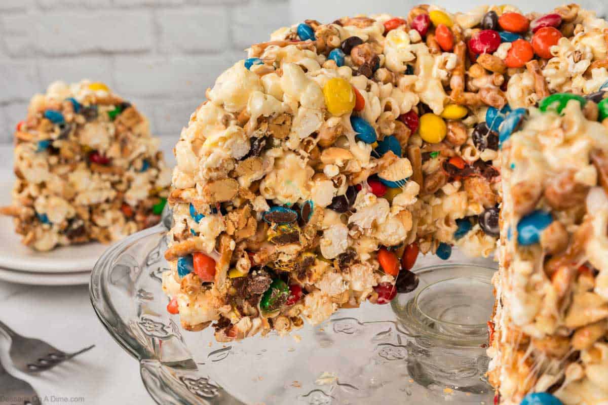 Popcorn cake on a pedestal being sliced. 