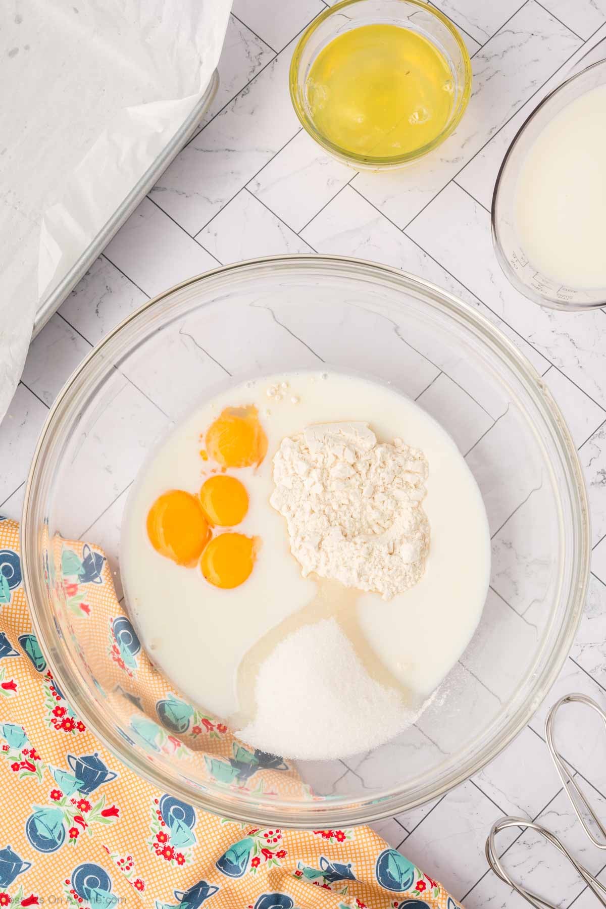 Mixing bowl with eggs, flour, sugar and milk. 