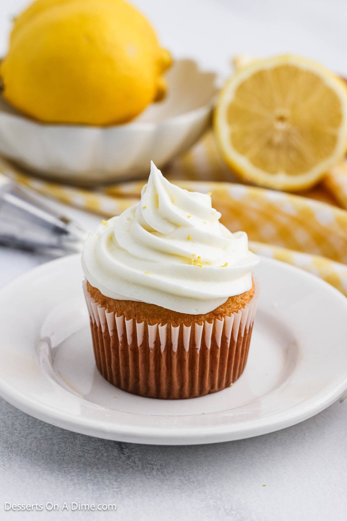Lemon Cream Cheese Frosting on a cupcake sitting on a white plate. 
