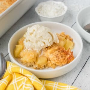Coconut Dump Cake in a bowl with ice cream.