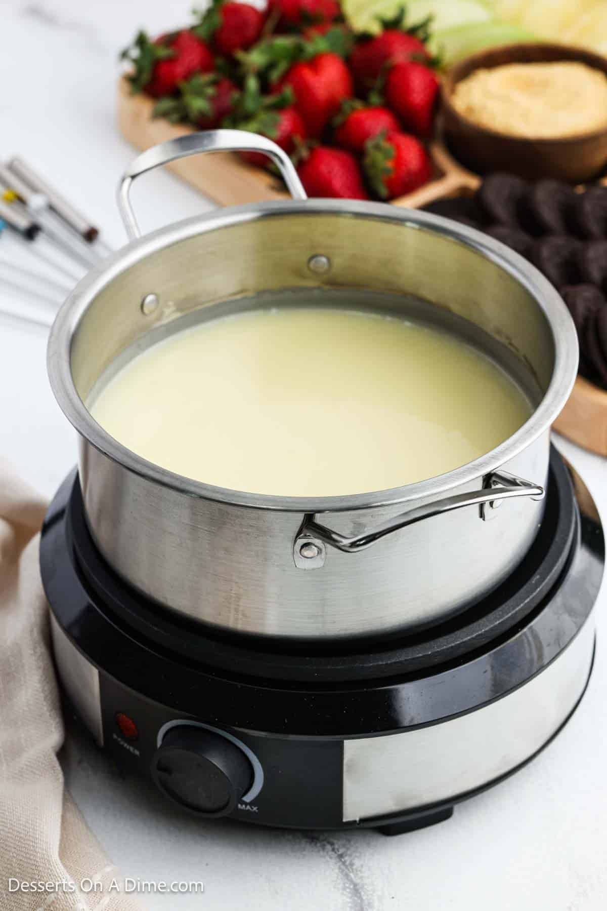 Fondue pot with mixture combined and melted ready to serve. 