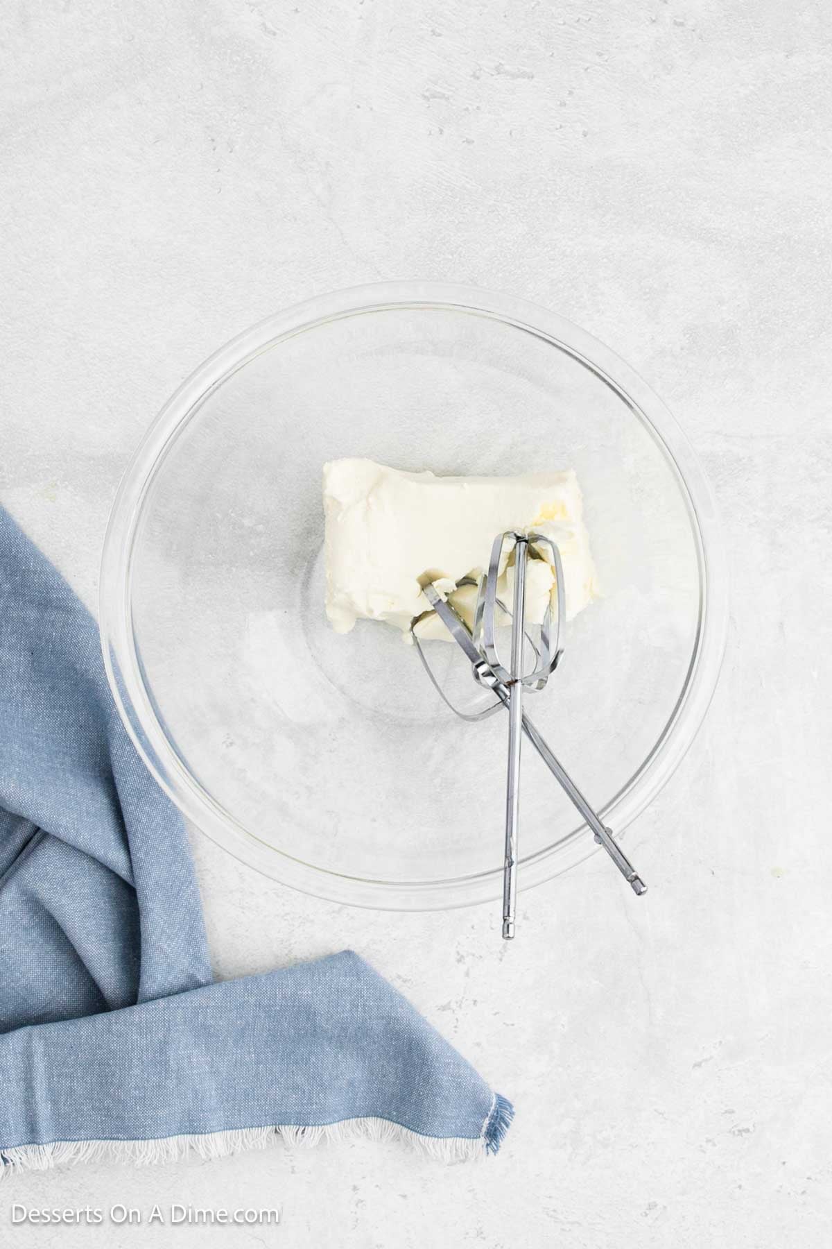 Cream cheese in a bowl with beaters. 
