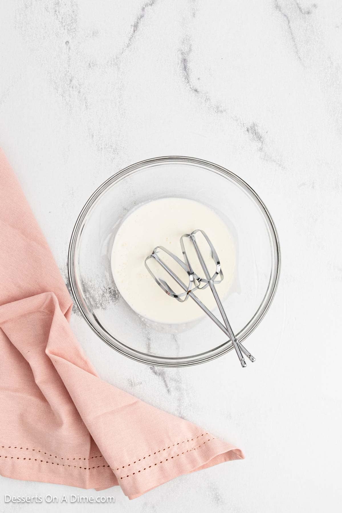 Heavy whipping cream in a bowl with beaters. 