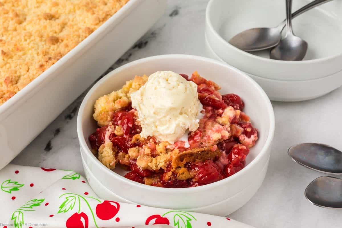 Cherry Cheesecake Dump Cake in a bowl topped with ice cream. 