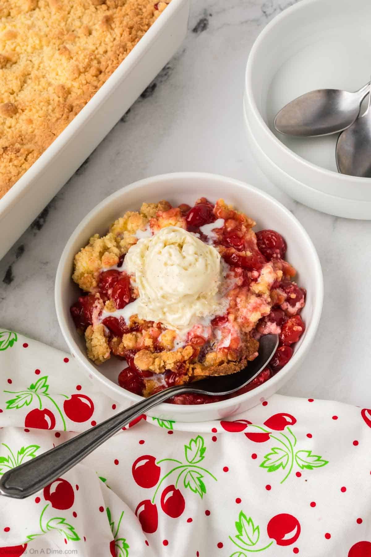 Cherry Cheesecake Dump Cake in a bowl with ice cream and a spoon. 