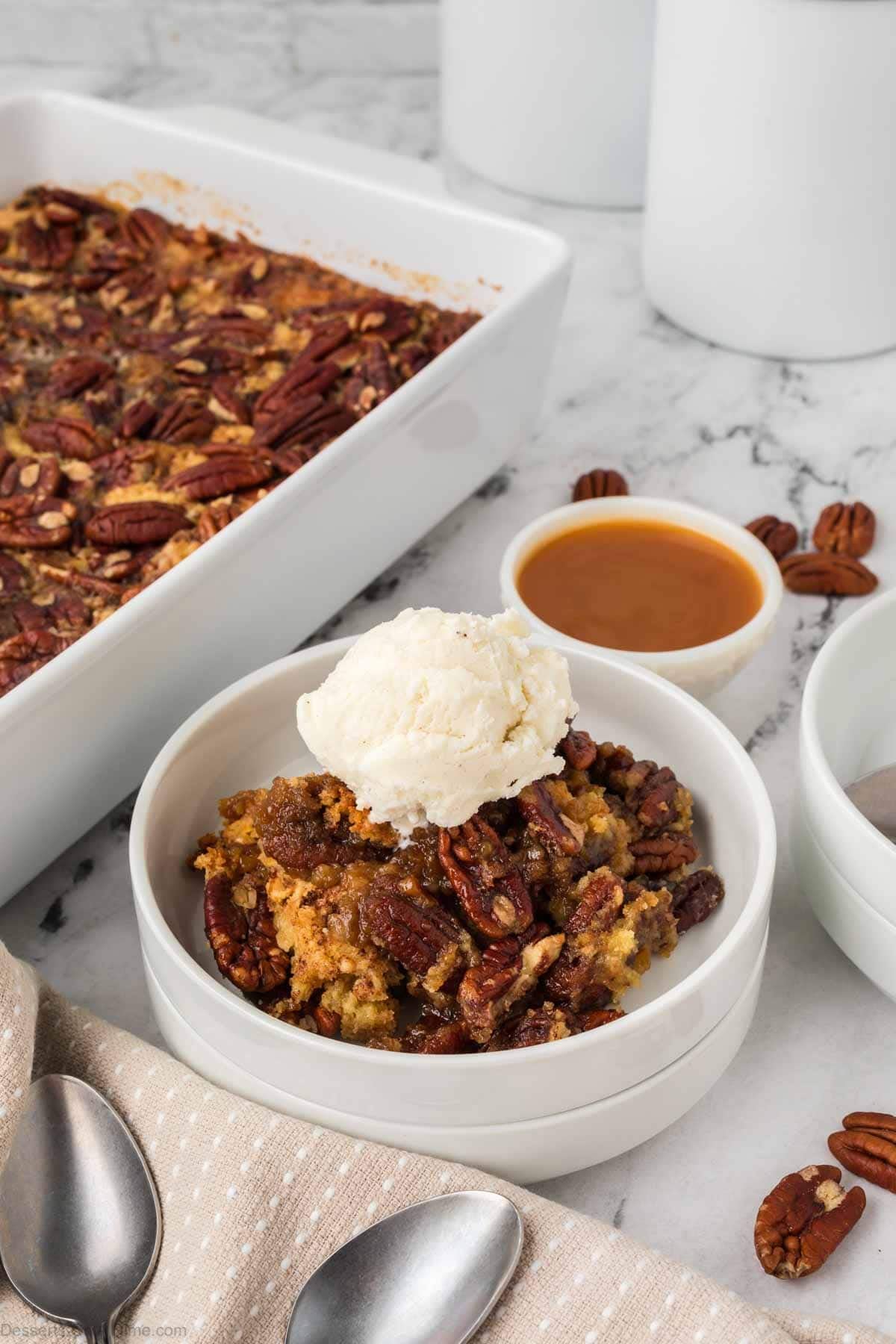 Pecan pie dump cake in a bowl with ice cream. 