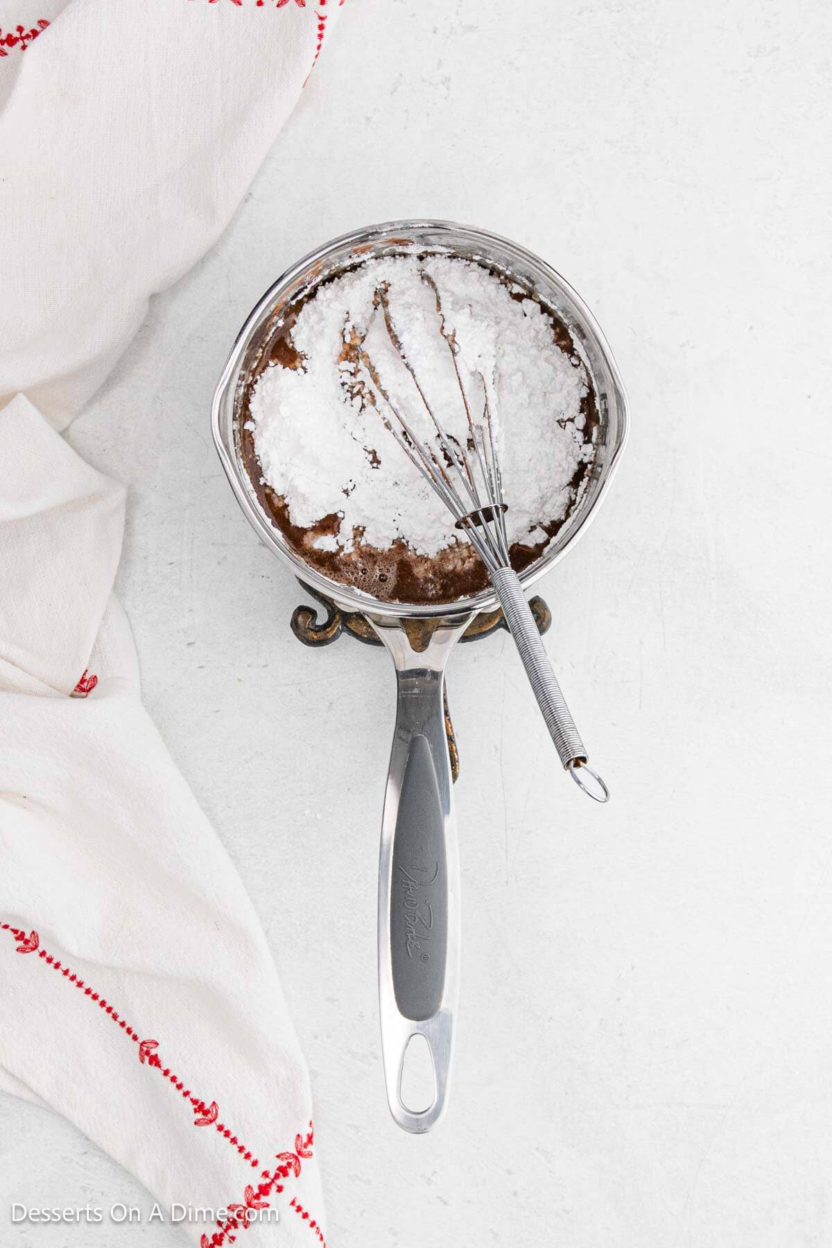 Powdered sugar whisked into mixture in pan. 