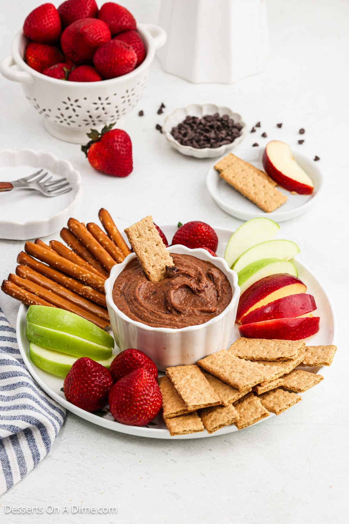 Chocolate Hummus surrounded by fruit and pretzels.