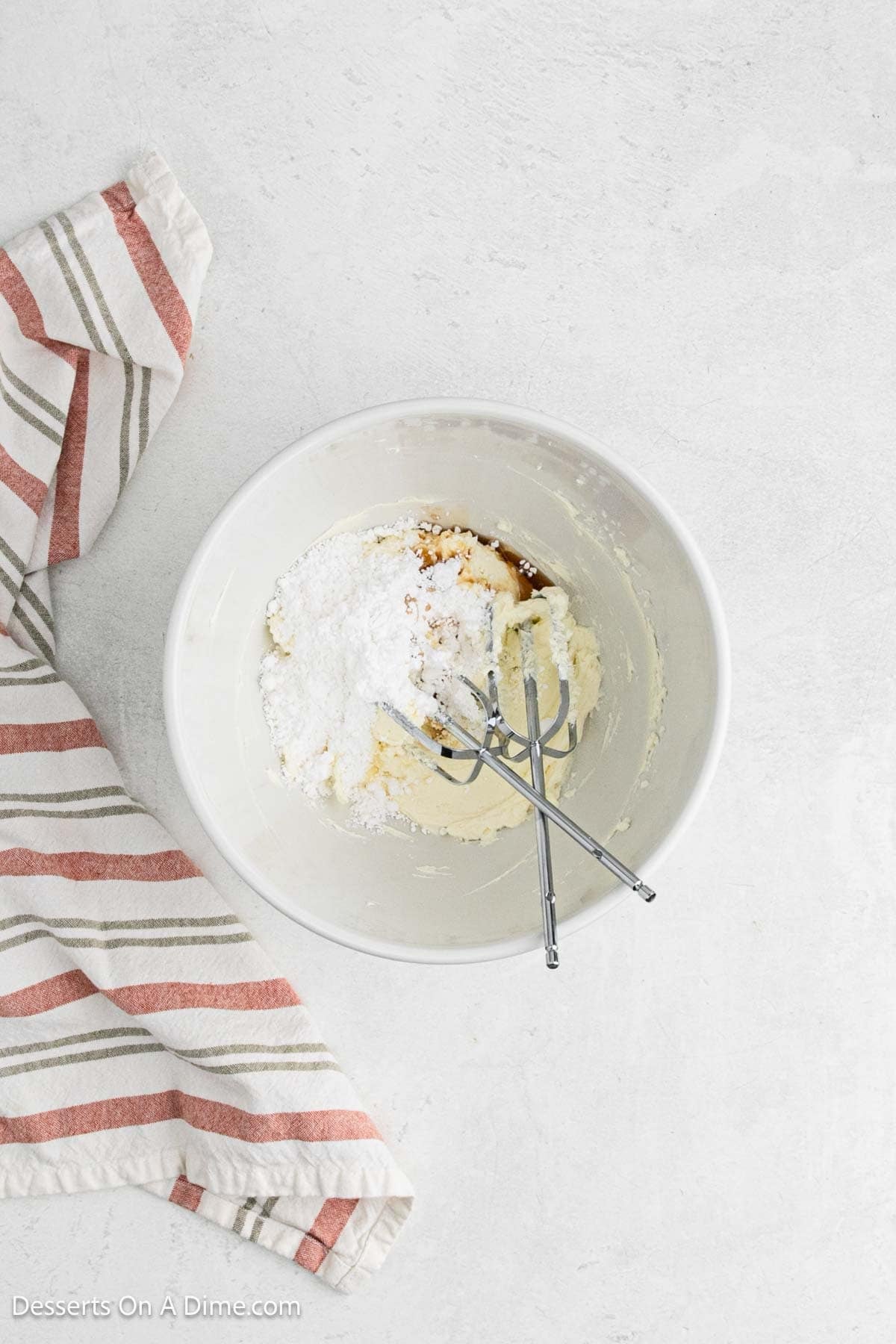 Powdered sugar and vanilla added to cream cheese in a bowl.
